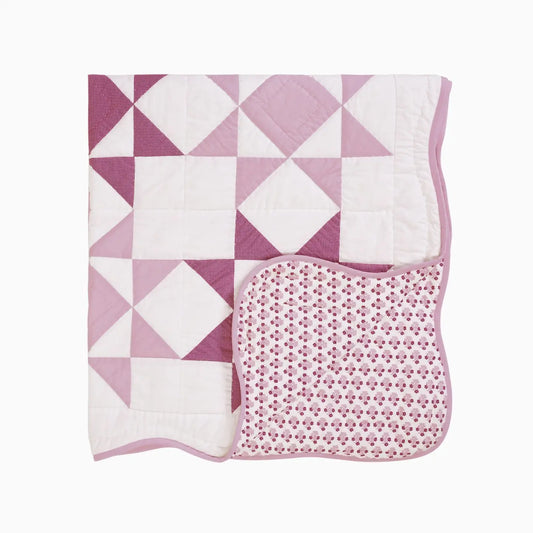 Pink and white quilt with geometric pattern on a white background
