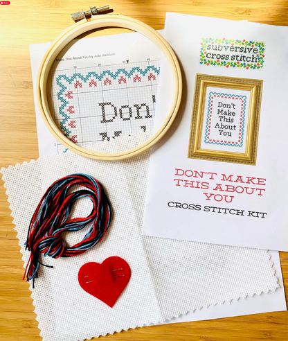 Cross stitch kit with hoop, thread, and printed design on a wooden surface