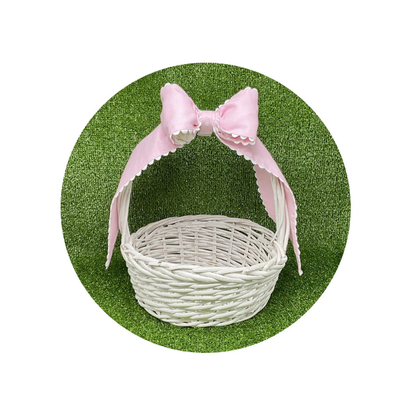 White wicker basket with a pink bow on a green background