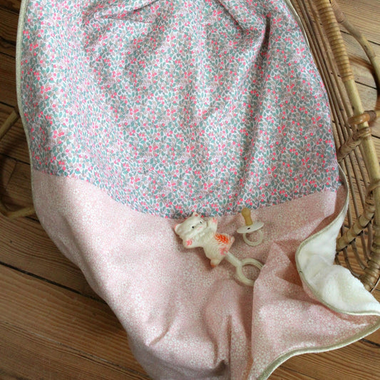 Floral-patterned baby bouncer seat on a wooden floor